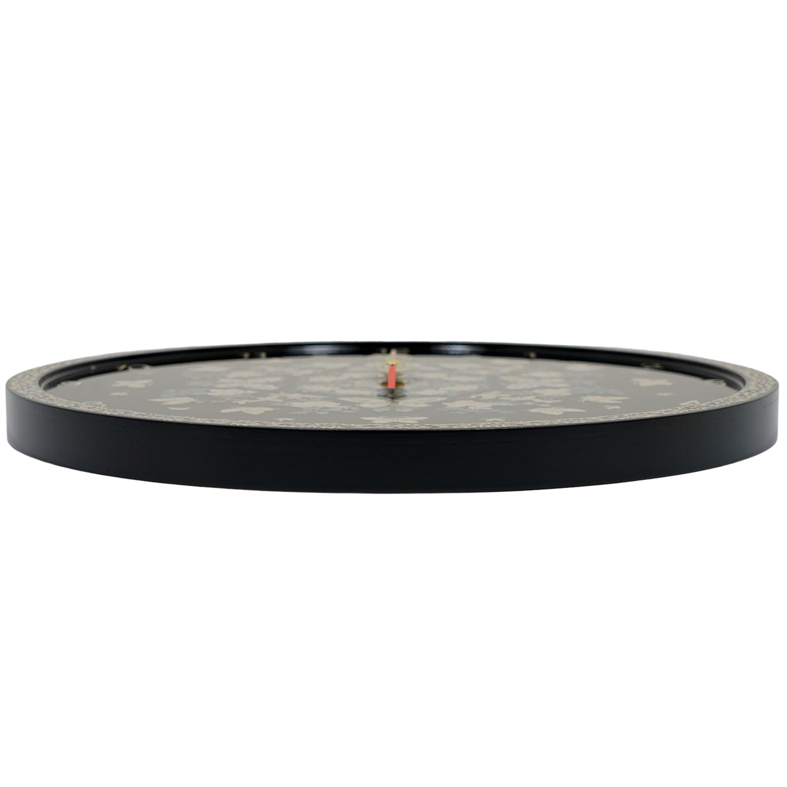 Side view of a round wall clock with a black face featuring subtle "Mother of Pearl" flower designs. The clock has a black exterior rim and a red central hand. The edge of the face has a patterned border.