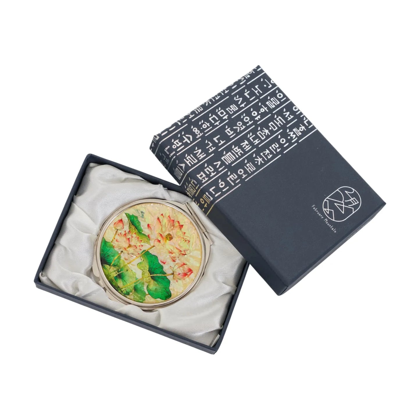 A decorative compact mirror with pink and yellow flowers, set in a dark blue gift box with Korean text