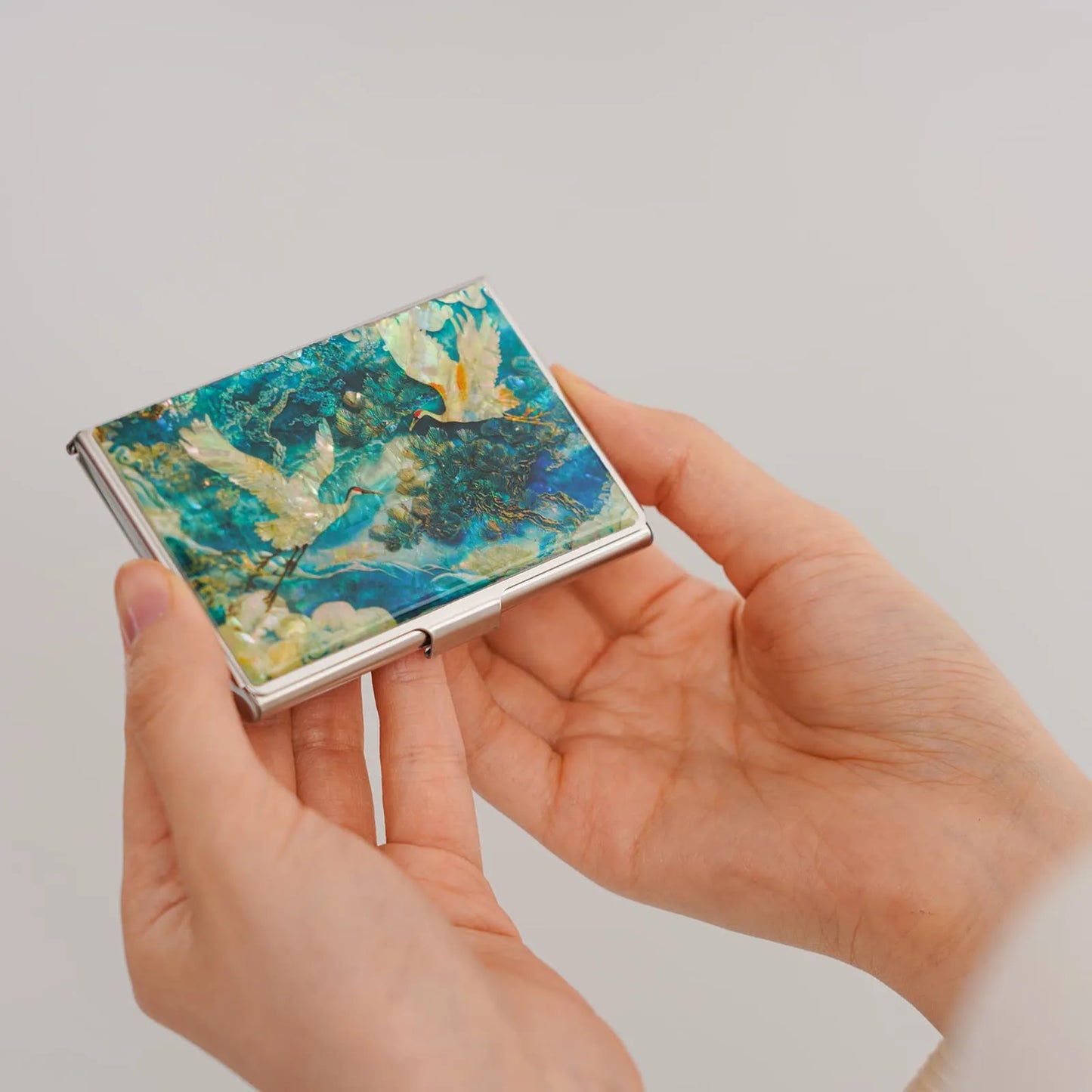 Hand holding a small rectangular object with a colorful, abstract design on a plain background