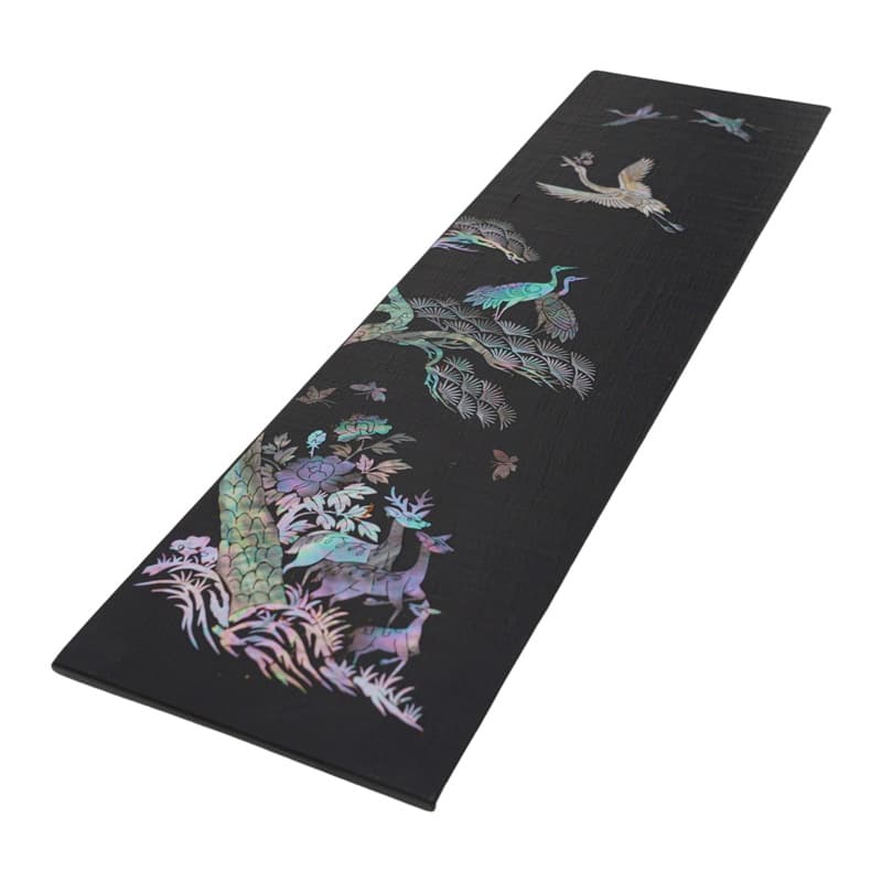 A long wooden tray wrapped in rectangular hemp cloth with a vibrant mother-of-pearl deer design.