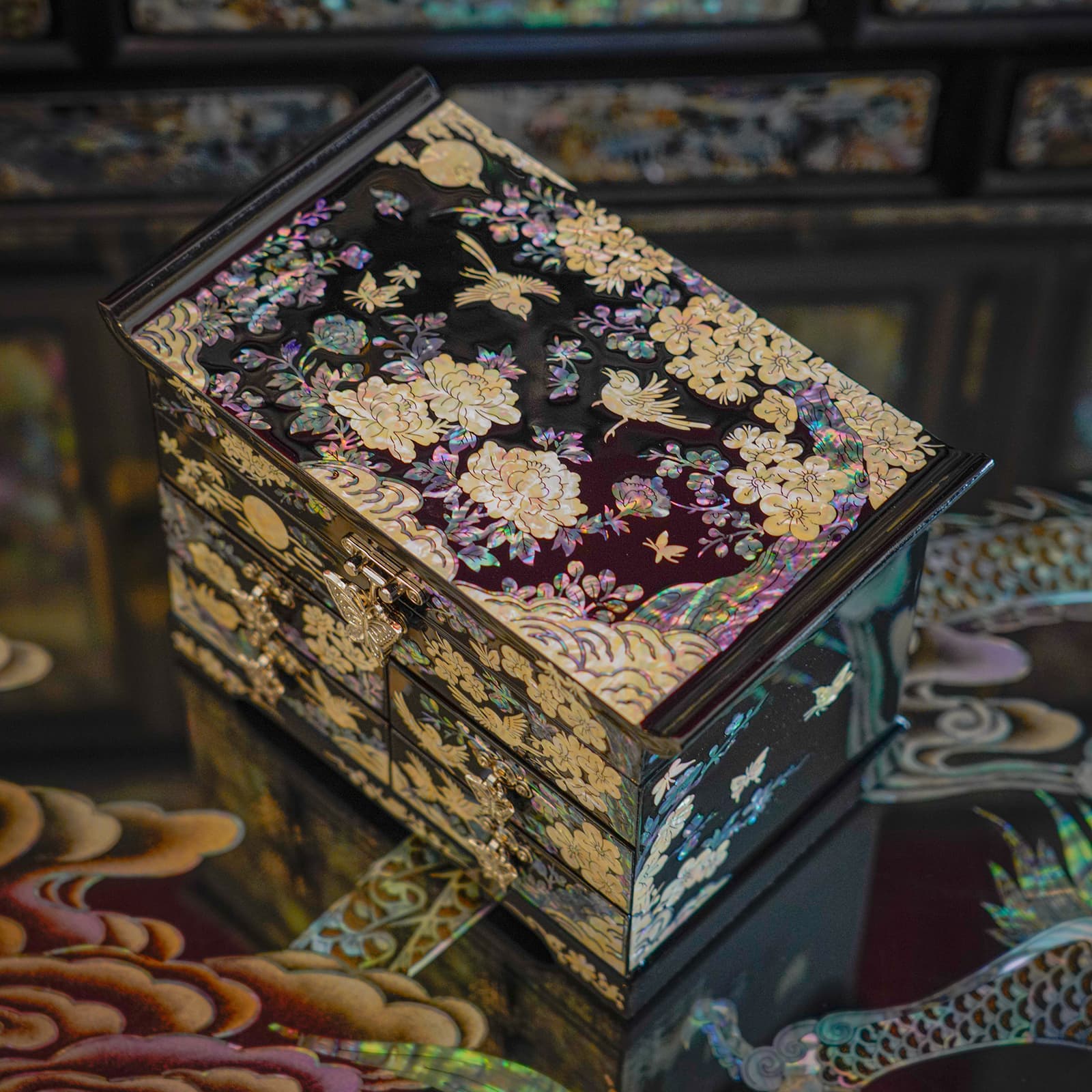 Angled view of a jewelry box with detailed mother-of-pearl inlay on a reflective surface.