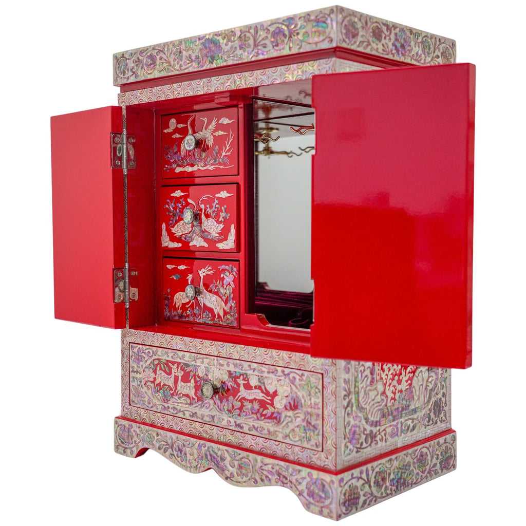 An open red cabinet with mother of pearl inlay depicting Asian scenes, brass hinges, and a mirror inside the lid.