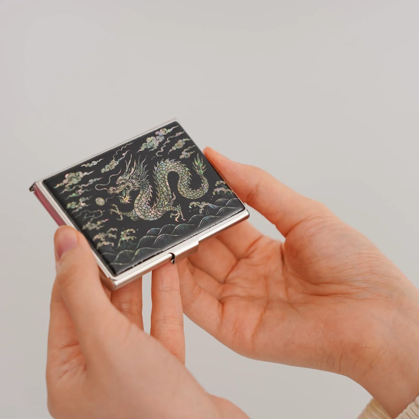 A decorative rectangular case featuring a gold dragon surrounded by clouds and waves on a black background