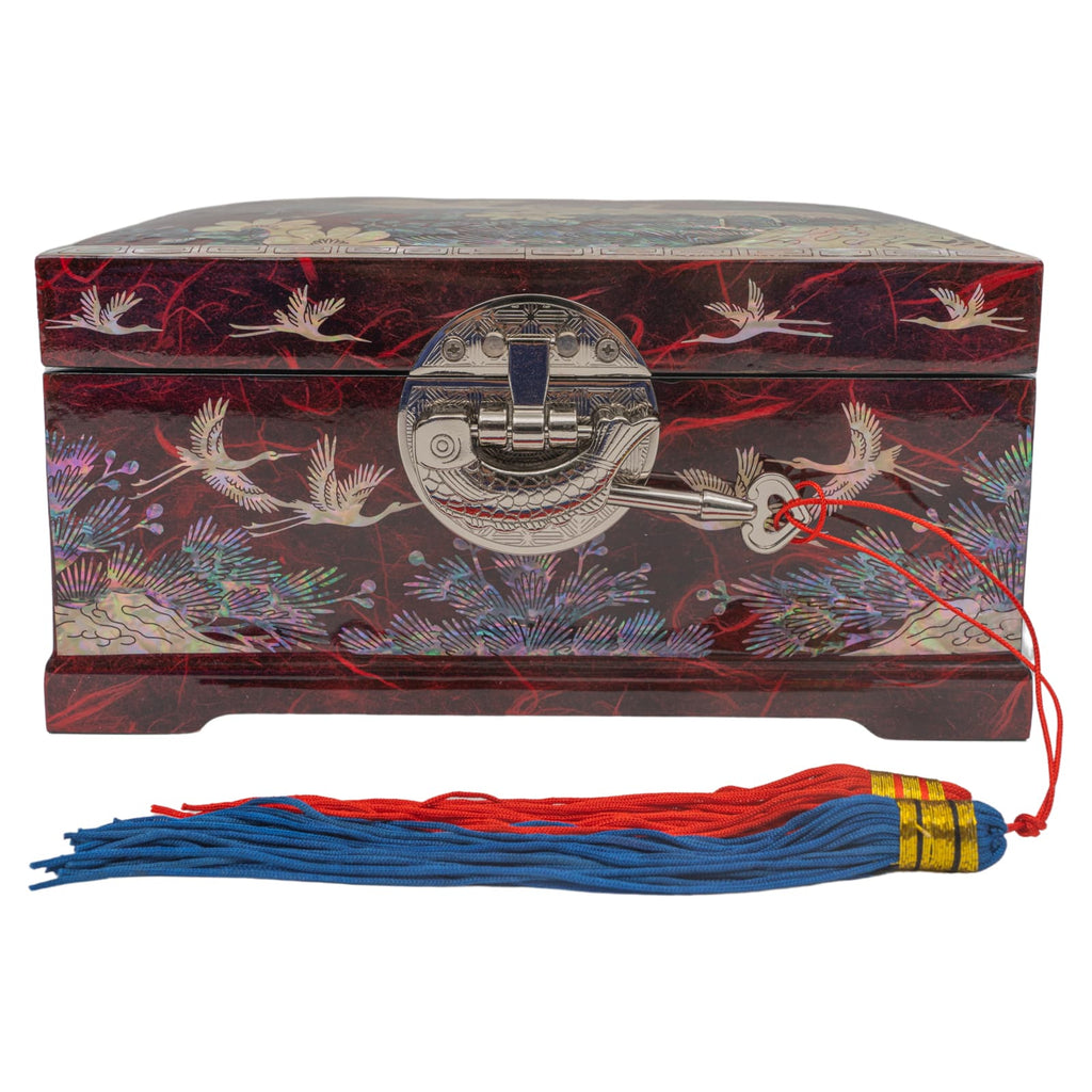 A red Mother of Pearl box with a silver clasp and an attached red and blue traditional Korean norigae tassel, set against a white backdrop.