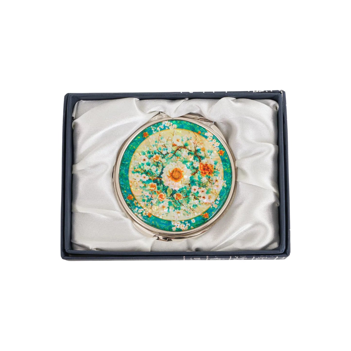 A round compact mirror with a decorative floral design featuring white, orange, and yellow flowers against a green and yellow background. The mirror is ( (8)