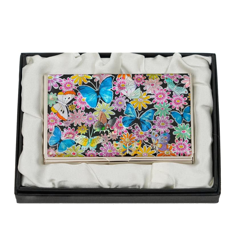 A business card case featuring a floral and butterfly pattern, nestled in a black gift box with a soft white interior.