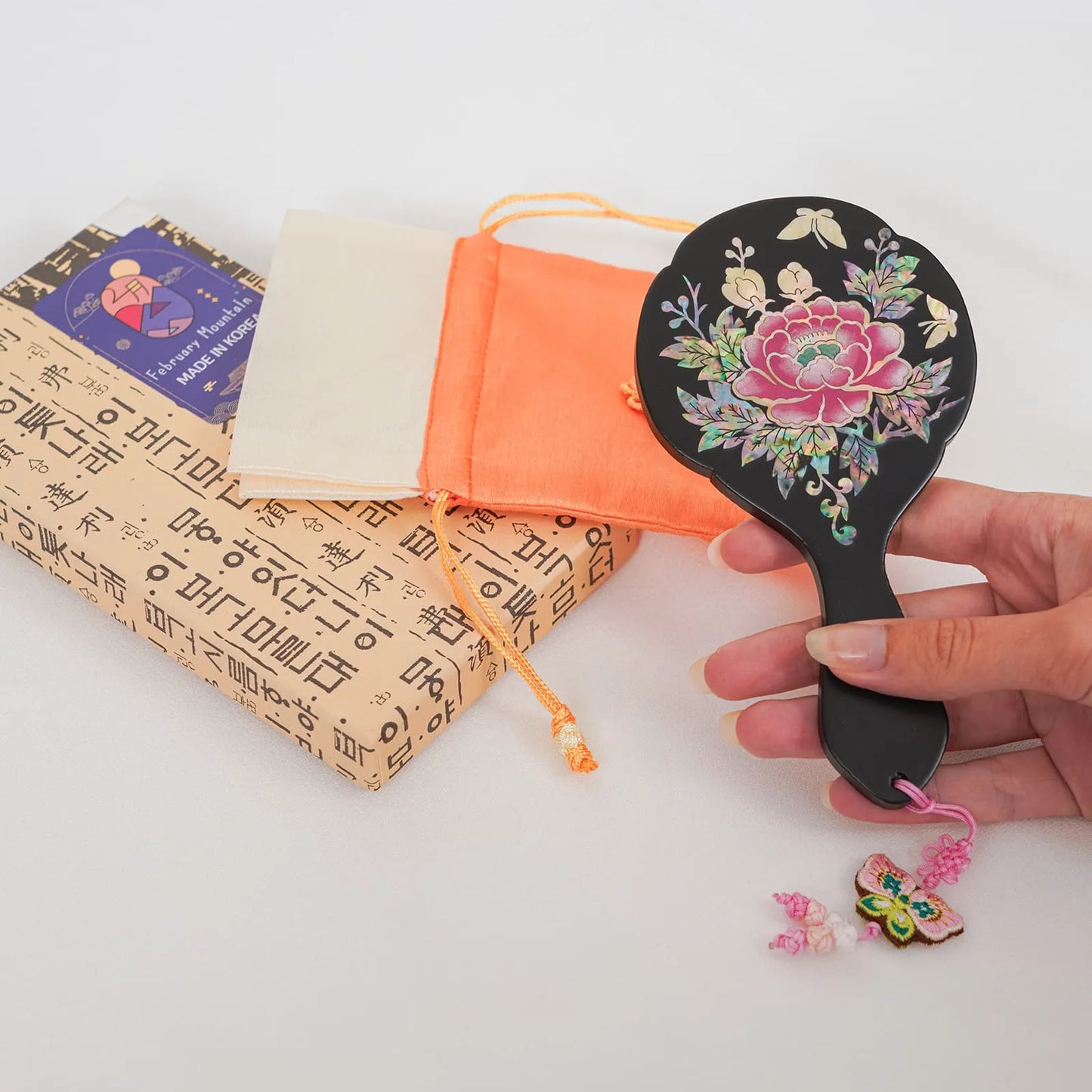 Black floral hand mirror with golden butterflies, paired with orange pouch and box
