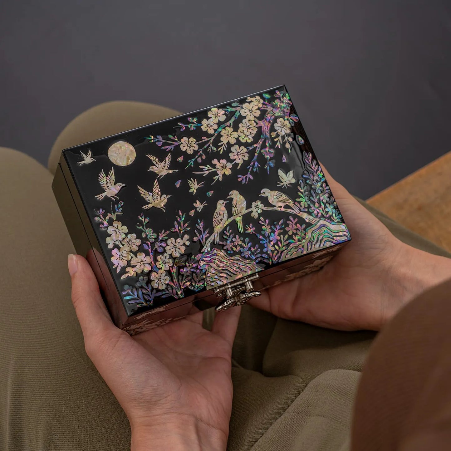 Black lacquer jewelry box with butterflies and peonies, held in front of the body