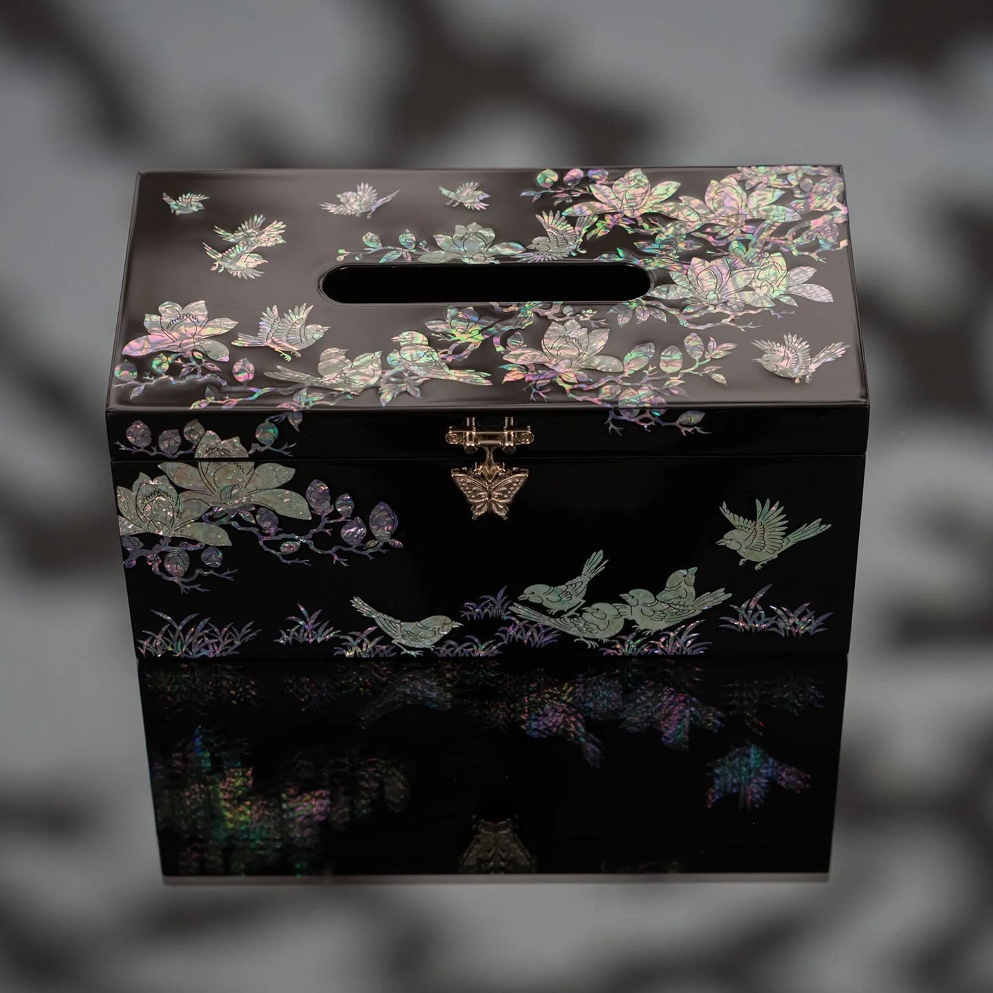 Black mother-of-pearl tissue box with iridescent floral bird design on reflective surface