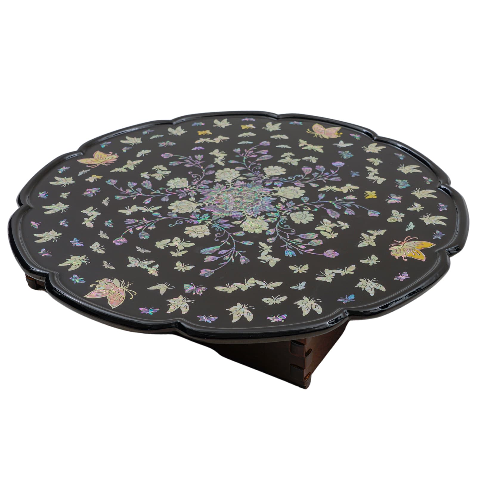 Black round table with intricate mother-of-pearl inlay of flowers and butterflies, featuring scalloped edges.