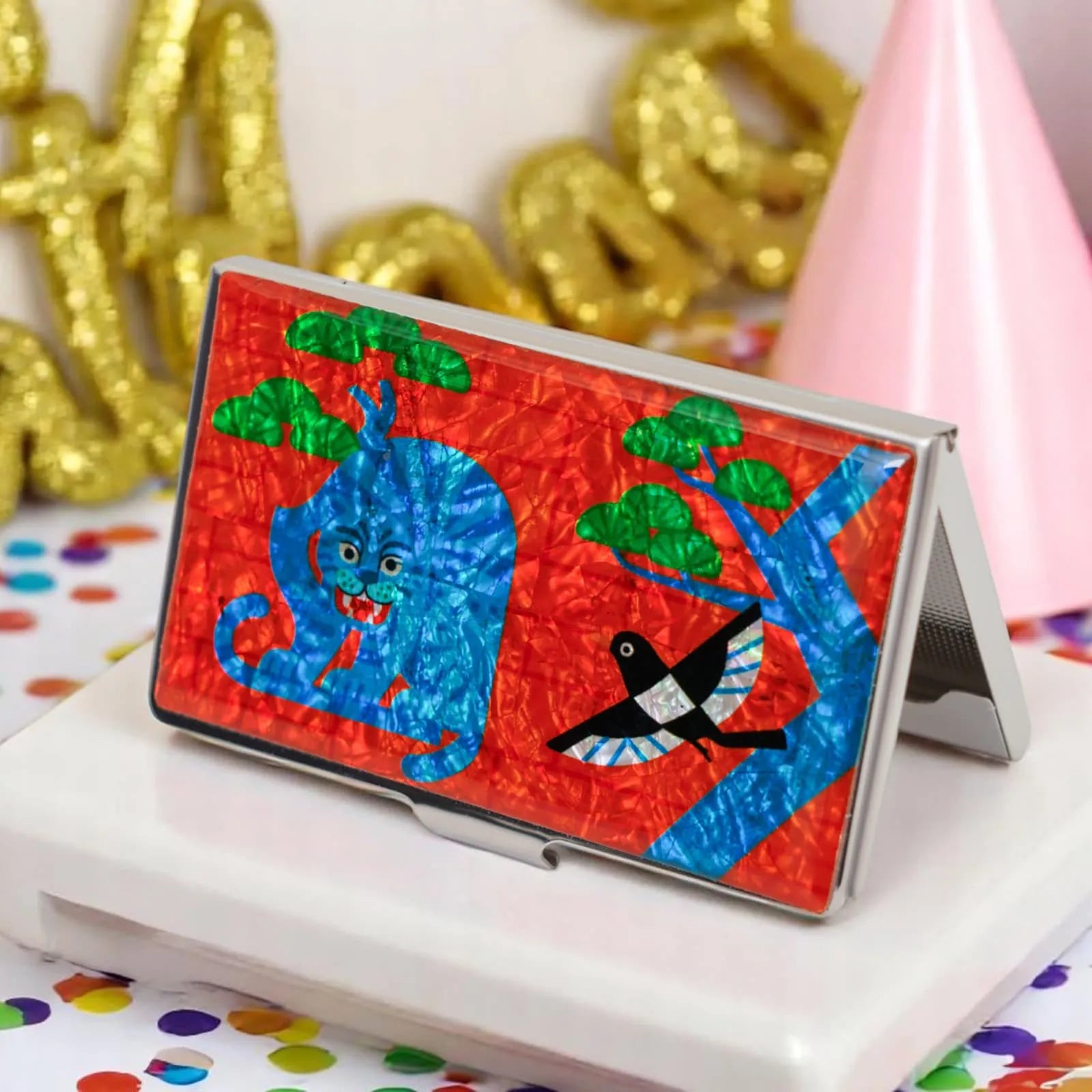 Card case with blue tiger and bird standing open on a white surface at a party