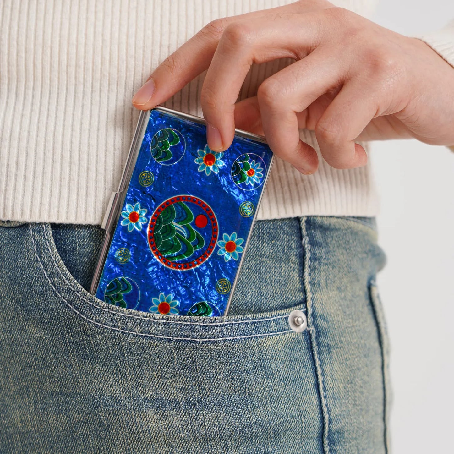 Card case with mountain motif being placed into a jeans pocket