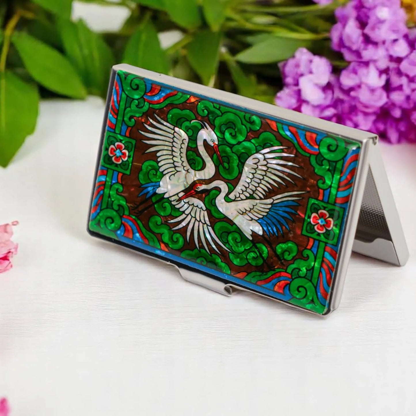 Card case with twin cranes design displayed on table with purple and pink flowers