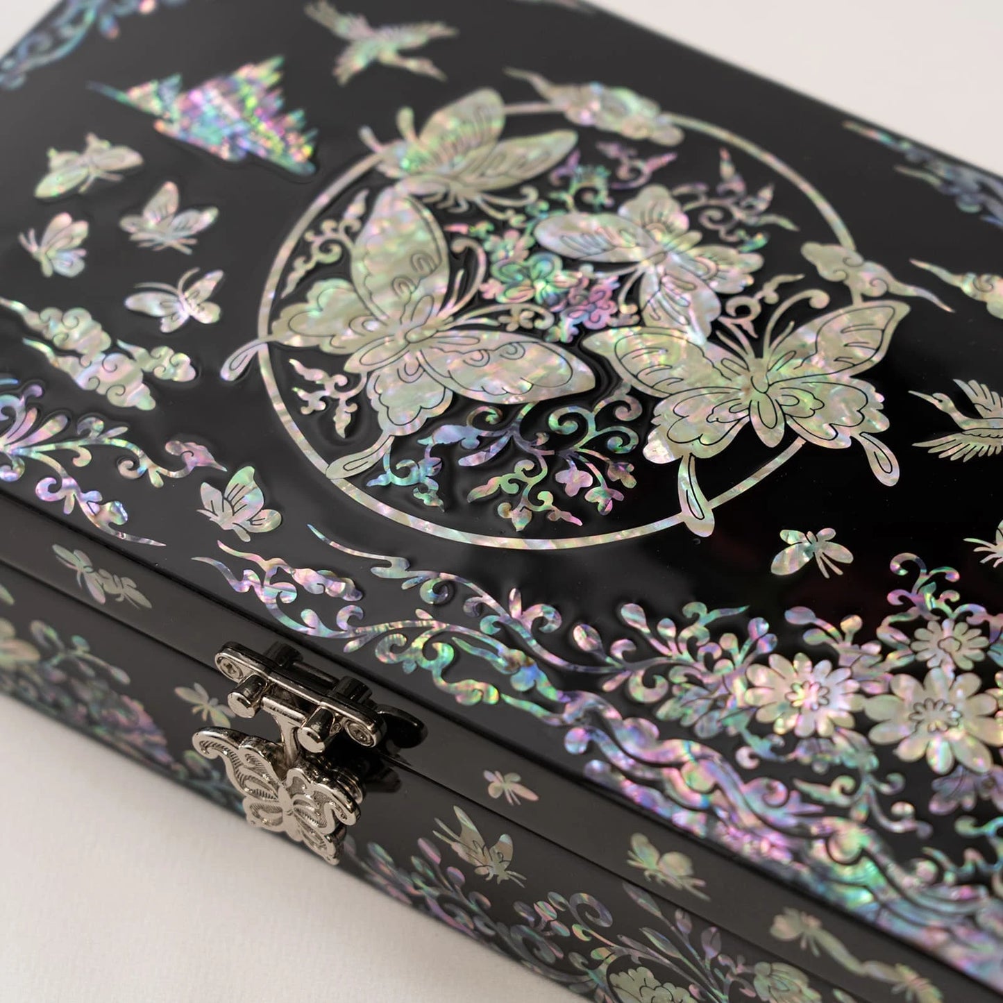 Close-up of a black jewelry box featuring a central circular mother-of-pearl design filled with beautifully detailed butterflies