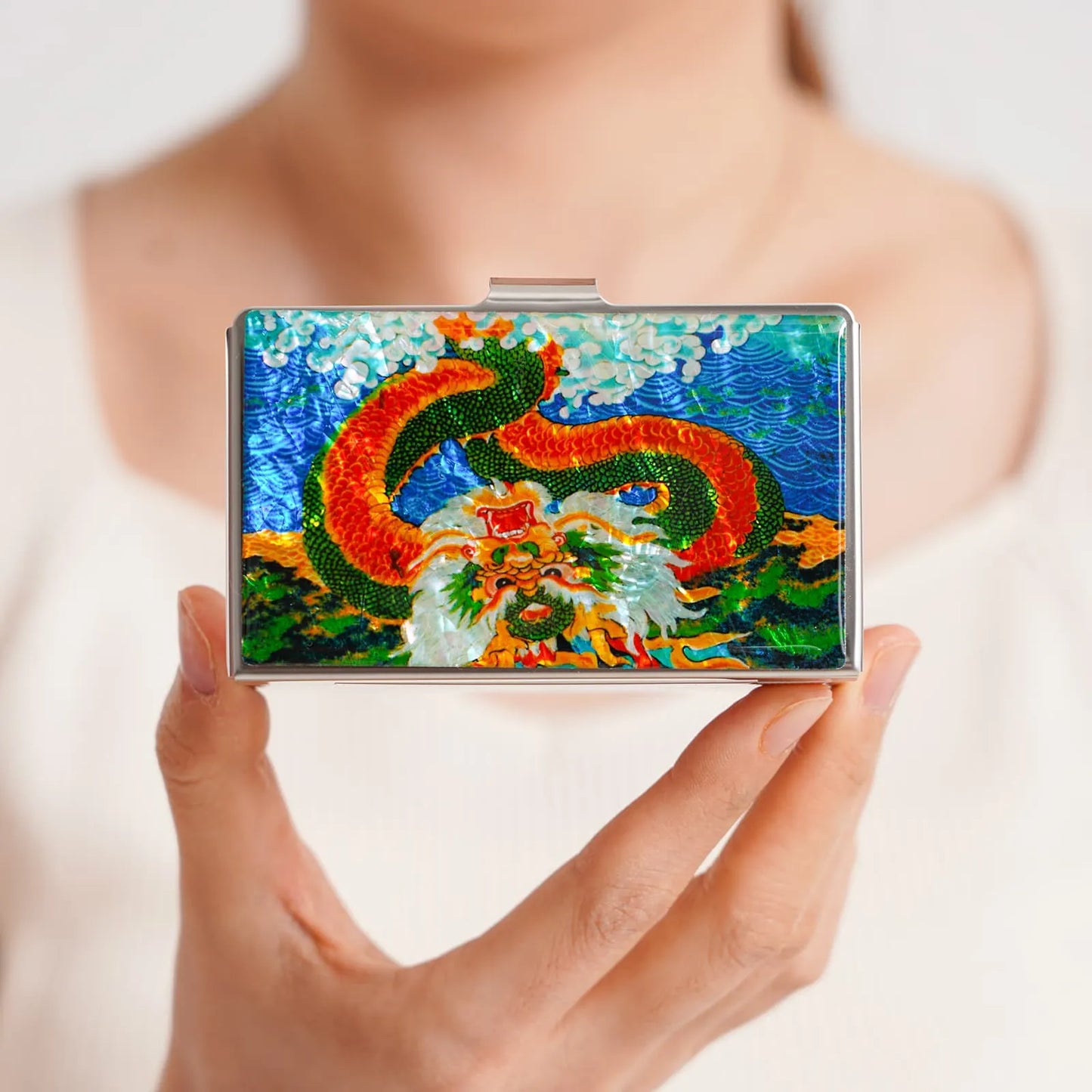 Colorful dragon design card case held in one hand against a neutral background