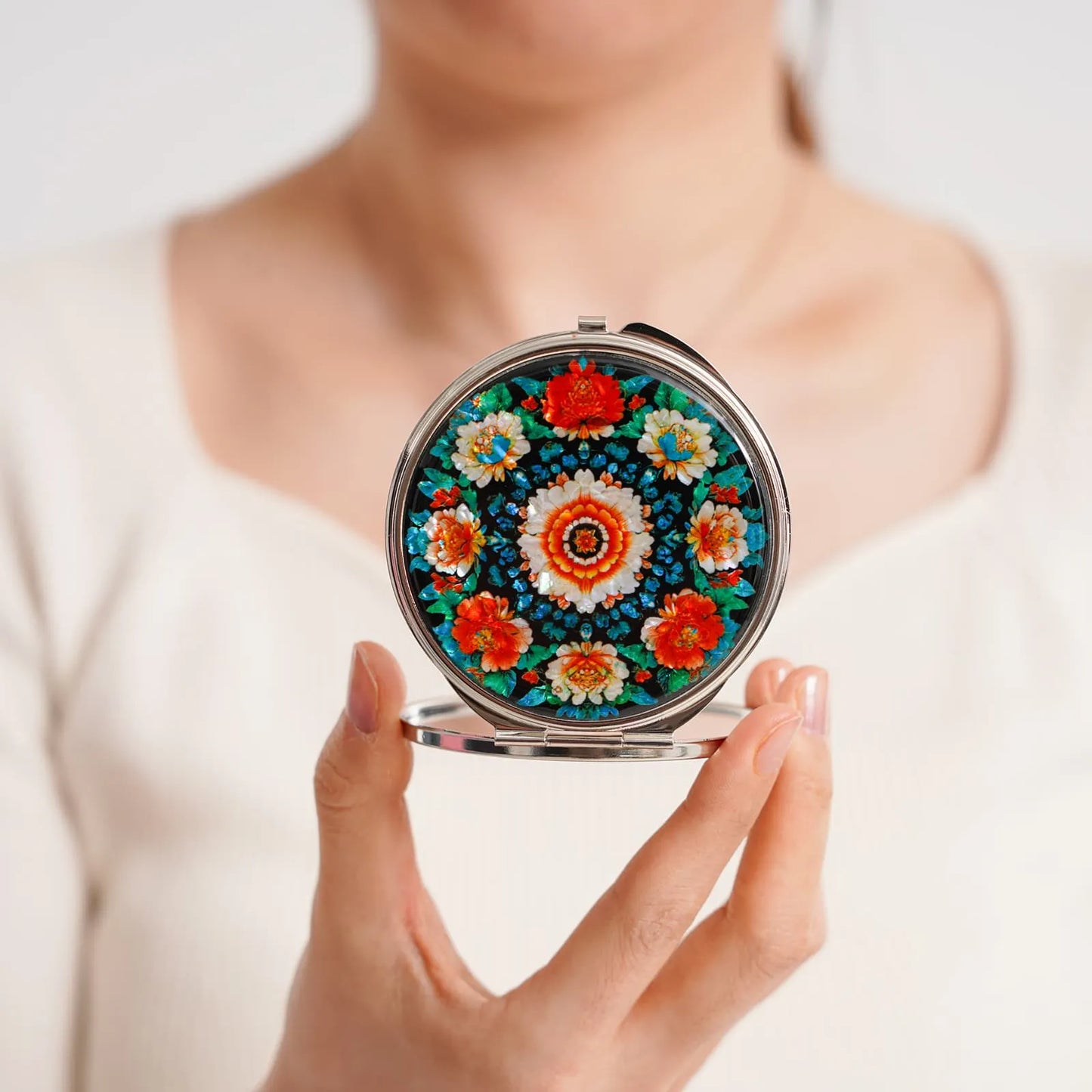 Floral mandala mirror held between hands with gift box beside
