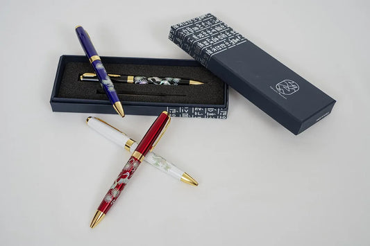 Four mother-of-pearl crane pens in various colors, with one displayed in a navy gift box