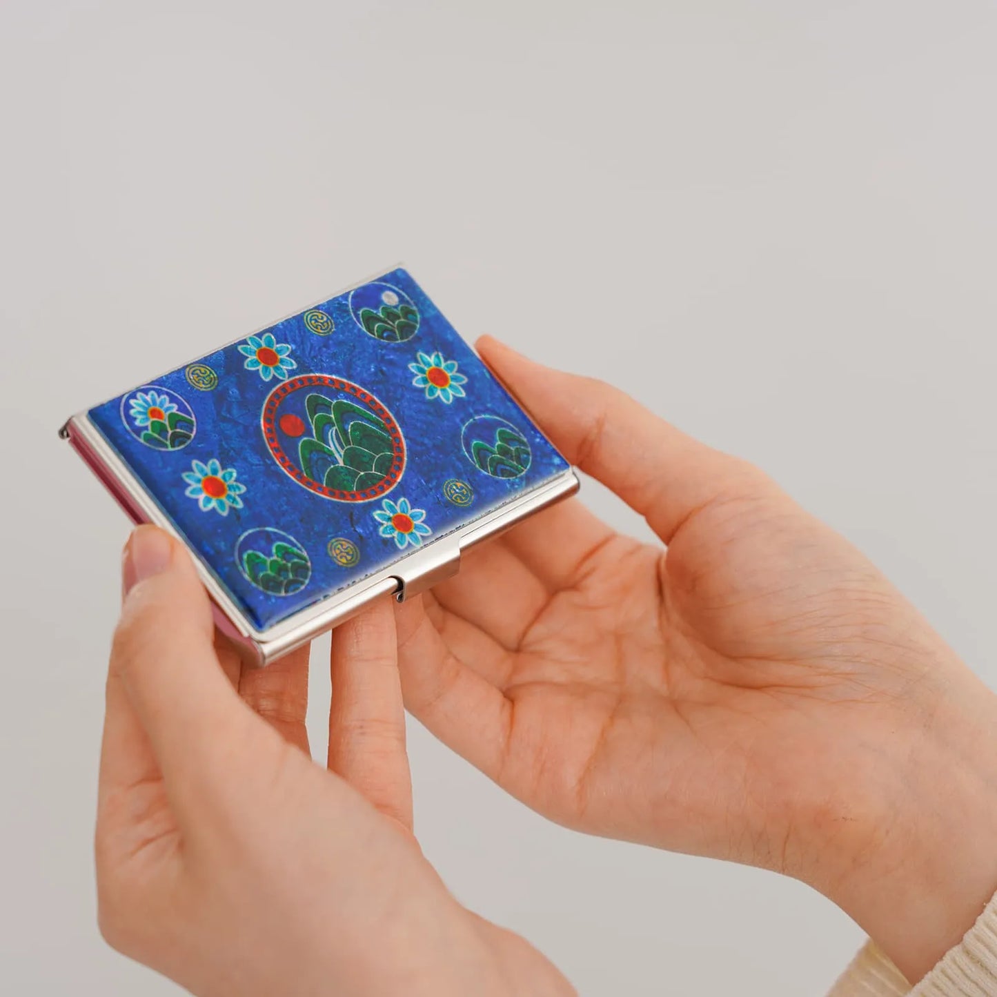Hands holding blue card case with traditional Korean-style inlay
