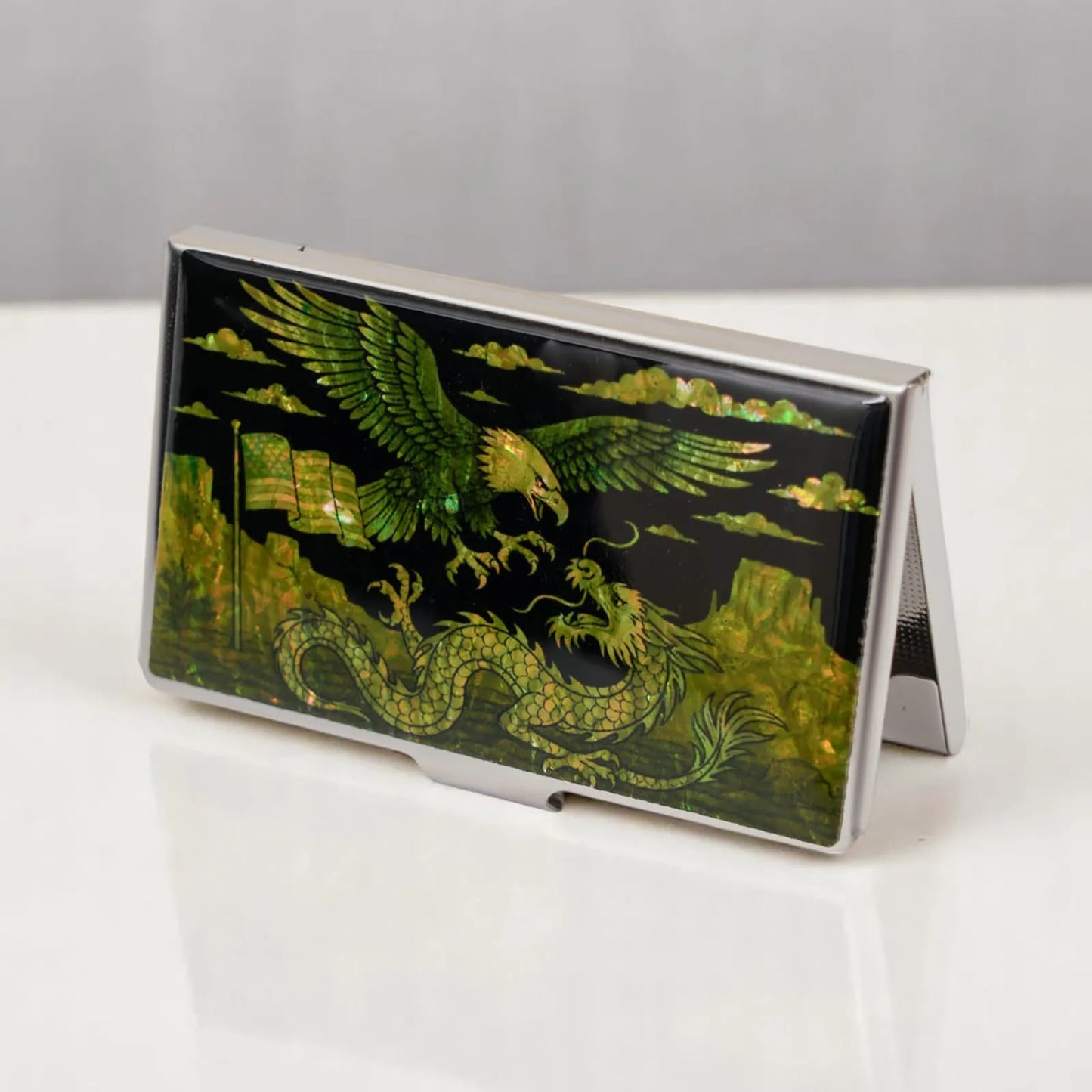 Mother-of-pearl card holder with eagle and dragon design on a white table