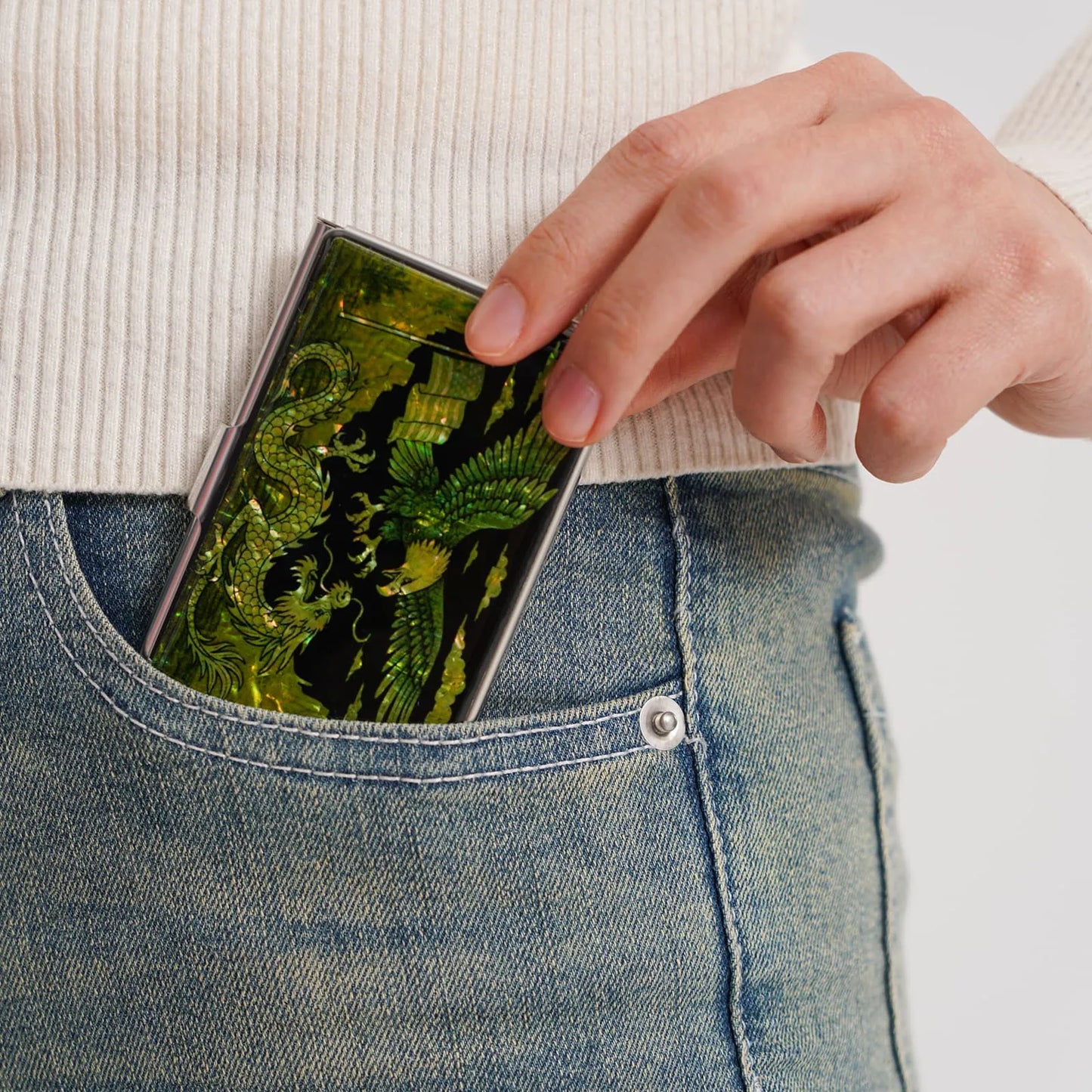 Putting a green eagle and dragon card case into a jeans pocket