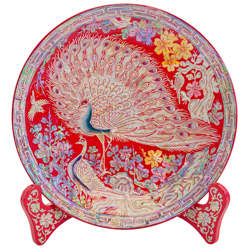 Red decorative plate featuring a peacock and floral design with a matching ornate stand.