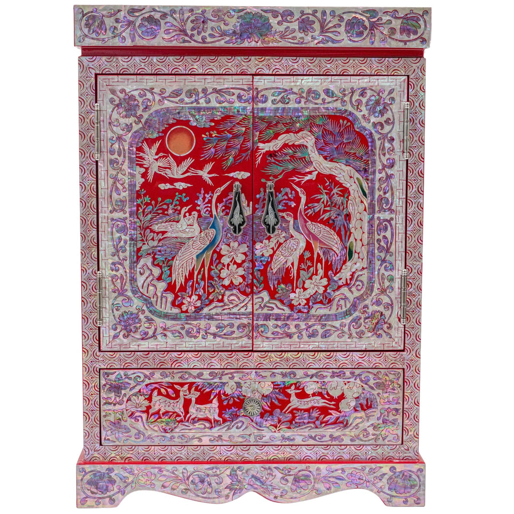 The cabinet is inlaid with mother of pearl, featuring cranes and florals on a red background, with intricate patterns and brass fixtures.