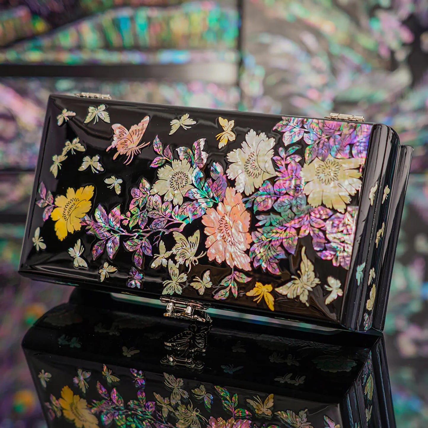This image shows a beautifully crafted mother-of-pearl jewelry box, adorned with intricate floral and butterfly designs on a lustrous black background, showcasing vibrant col