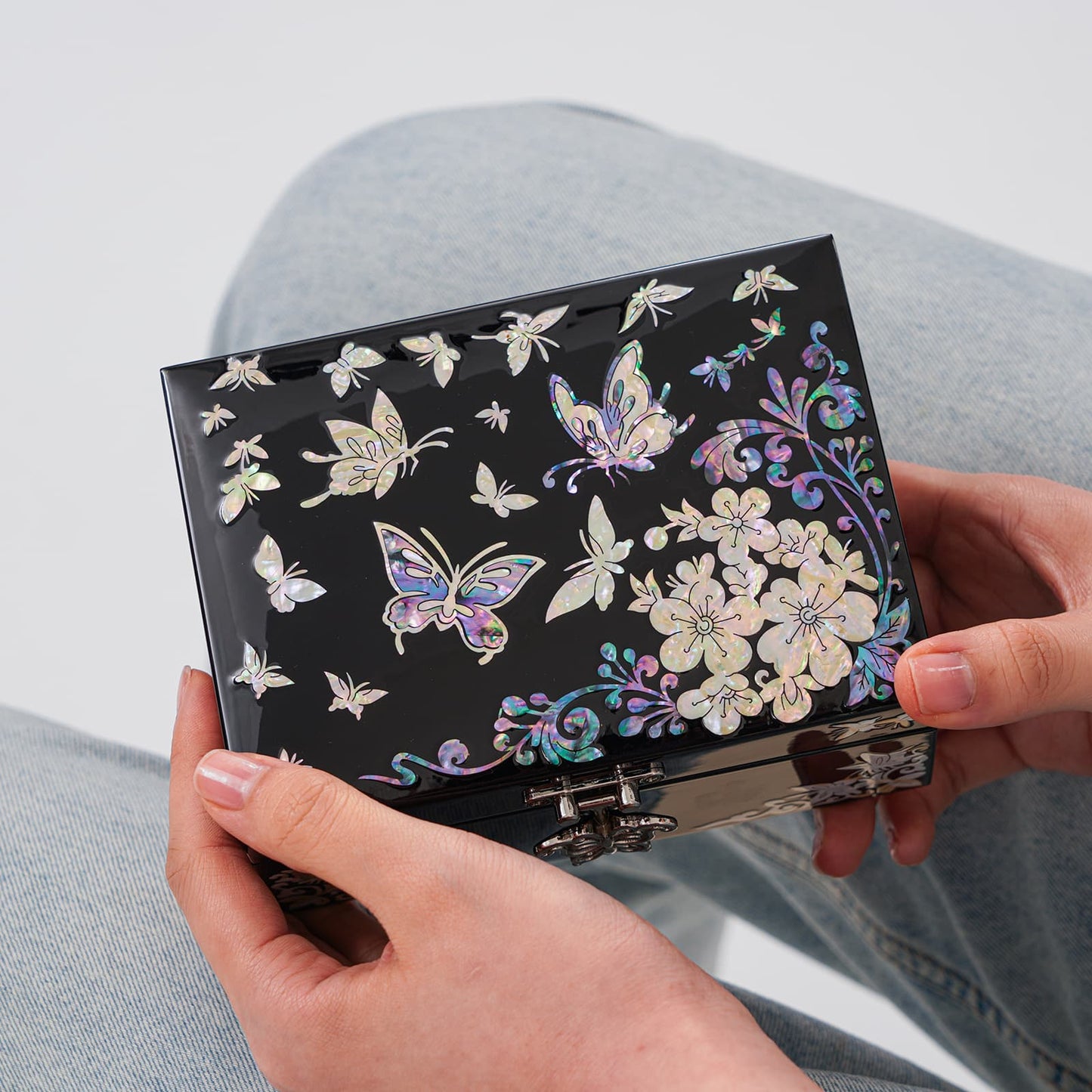 Traditional Korean jewelry box resting on a lap, decorated with floral mother-of-pearl patterns