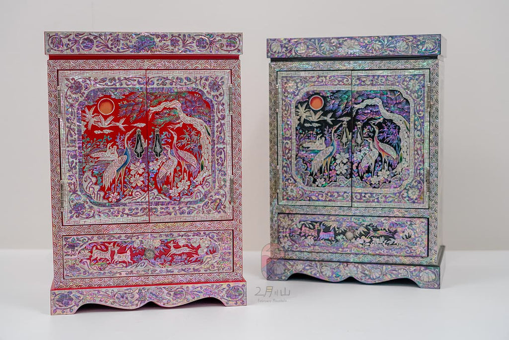 Two mother-of-pearl cabinets, one red and one black, each with a sun motif and crane designs, showcasing traditional inlay craftsmanship.