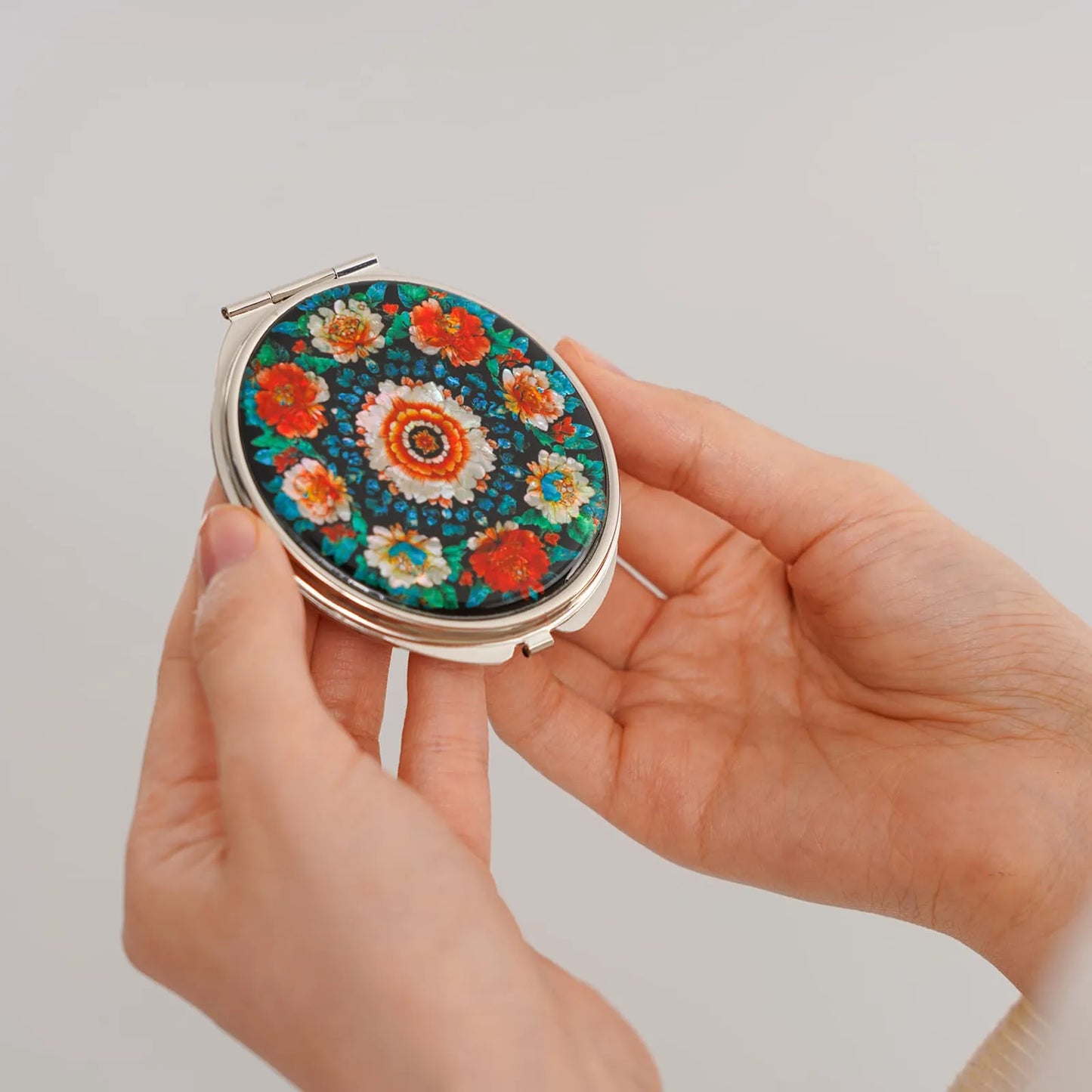 Woman holding floral compact mirror with peony design
