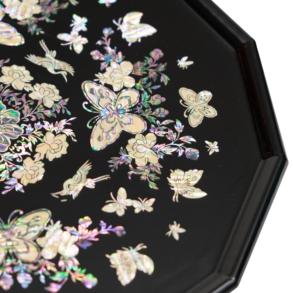 A close-up of a black octagonal tray with detailed mother-of-pearl inlay showcasing butterflies and flowers.