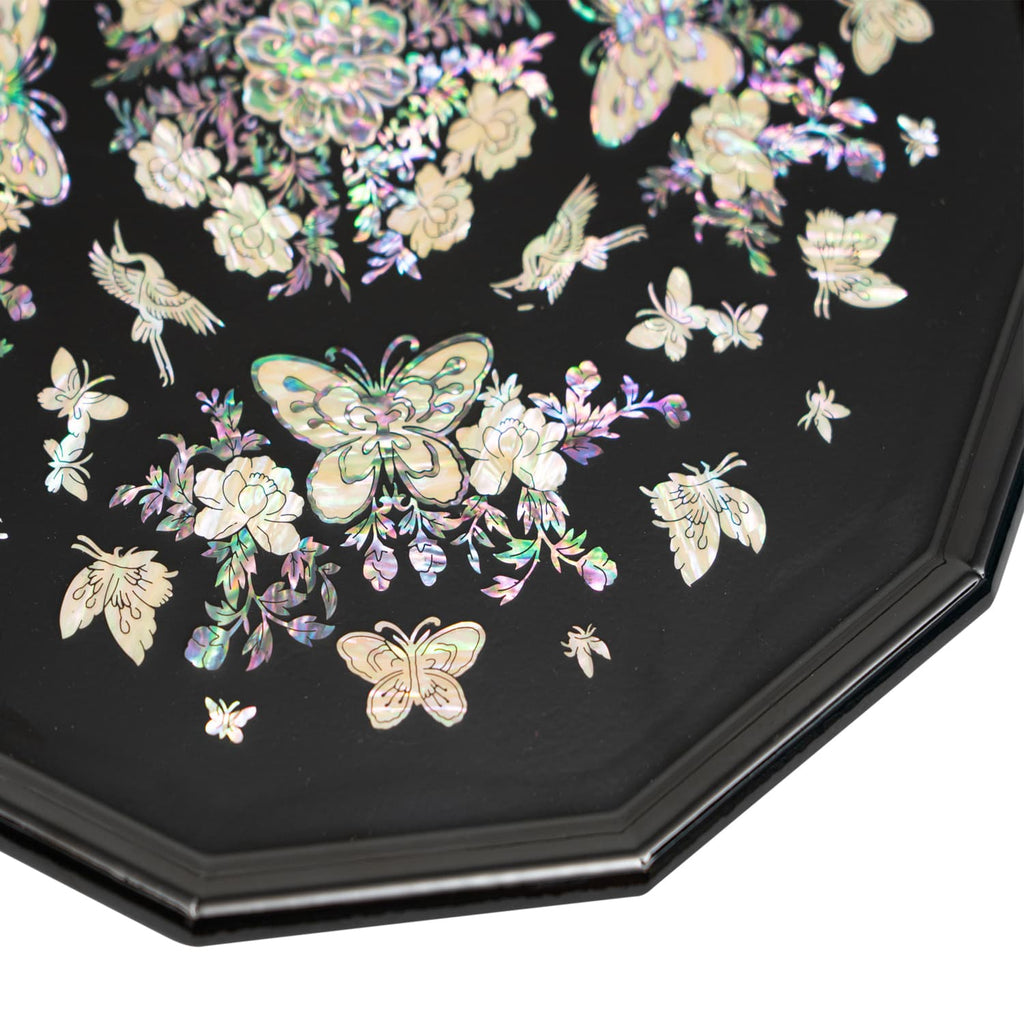 This image shows a segment of a black octagonal tray with a mother-of-pearl butterfly and floral design.