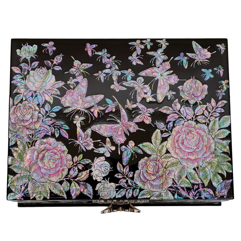 A jewelry box with a mother of pearl design of roses and butterflies on a black lacquer base, featuring a front clasp and intricate detailing.