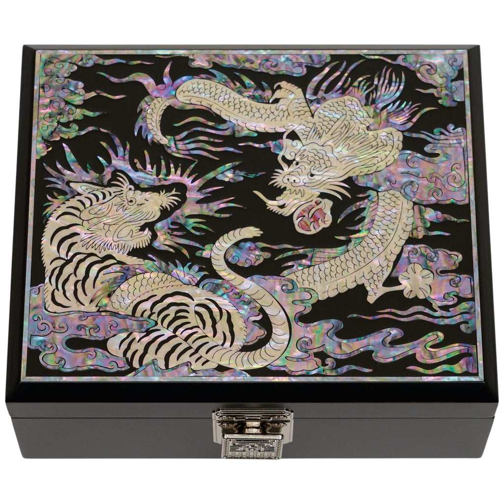 A box with mother of pearl inlay depicting a tiger and dragon, with a detailed metal clasp on the front.