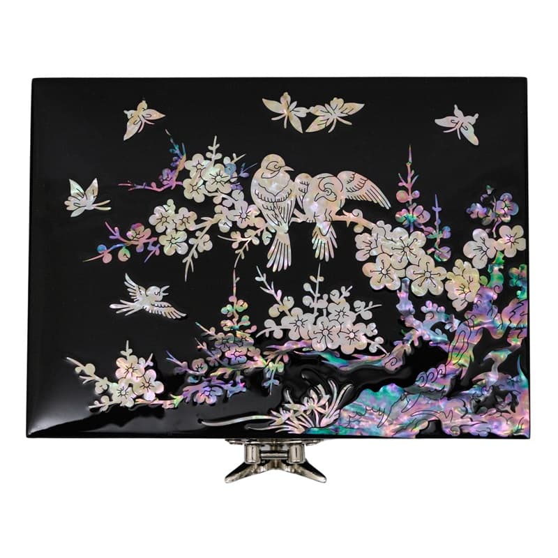 A black jewelry box featuring a mother-of-pearl design of a bird on a plum tree, with a butterfly clasp at the front.