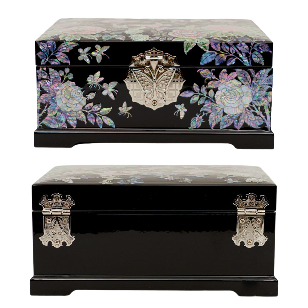 A black lacquered jewelry box adorned with mother of pearl inlay featuring floral and butterfly motifs, with a decorative metallic crest clasp on the front.