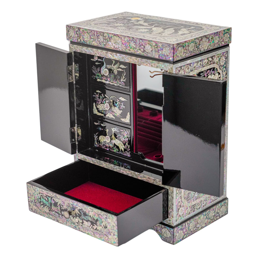 A black jewelry box with doors open to reveal a mirror and red velvet interior, and a lower drawer with a mother-of-pearl floral motif.