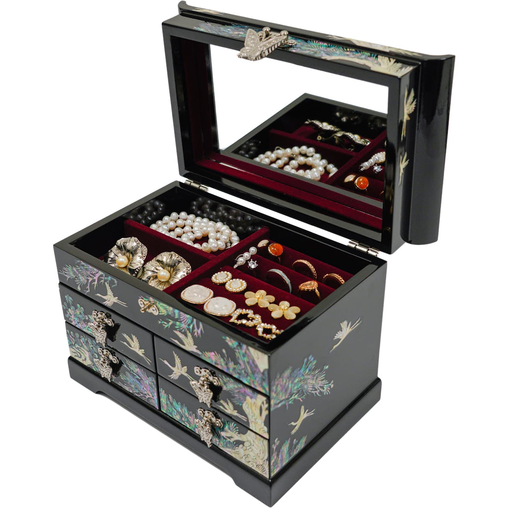 A black lacquered mother-of-pearl jewelry box with a mirror, multiple drawers filled with assorted jewelry, showcasing a traditional Korean design with cranes and floral patterns. Elegant and functional, it's a stylish piece for safekeeping treasures.