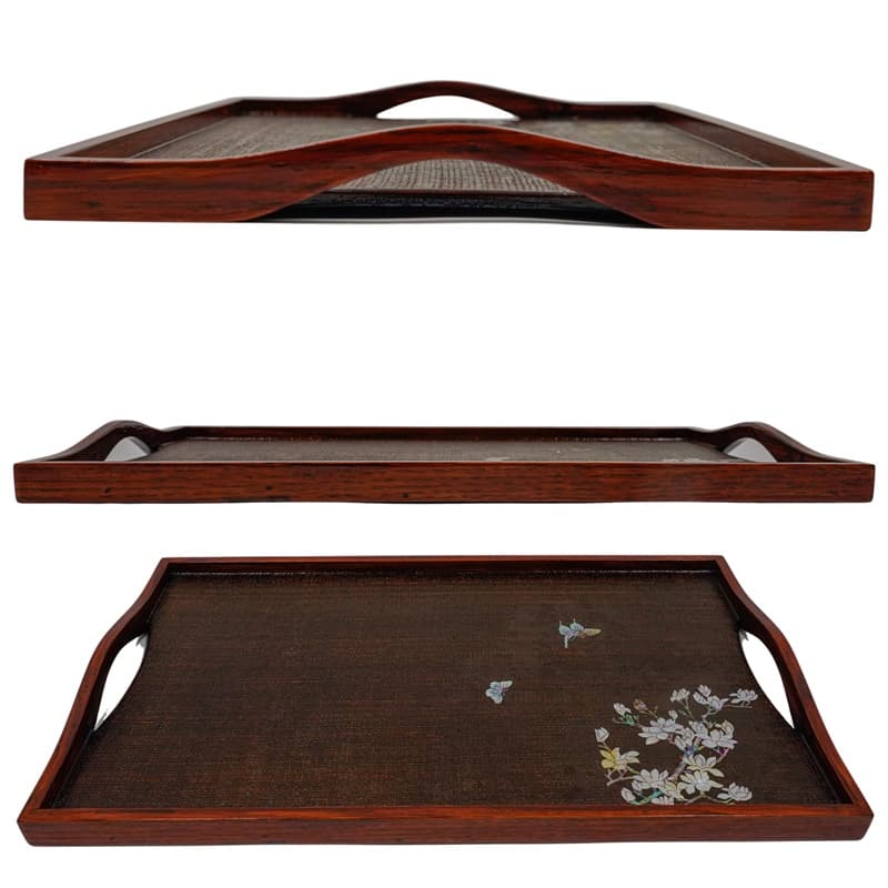 A dark, wooden tray with a mother-of-pearl inlay design, viewed from three angles, with a cutout handle.