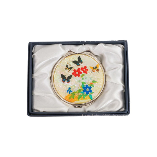 A decorative compact mirror featuring colorful flowers and butterflies, set in a satin-lined dark gift box