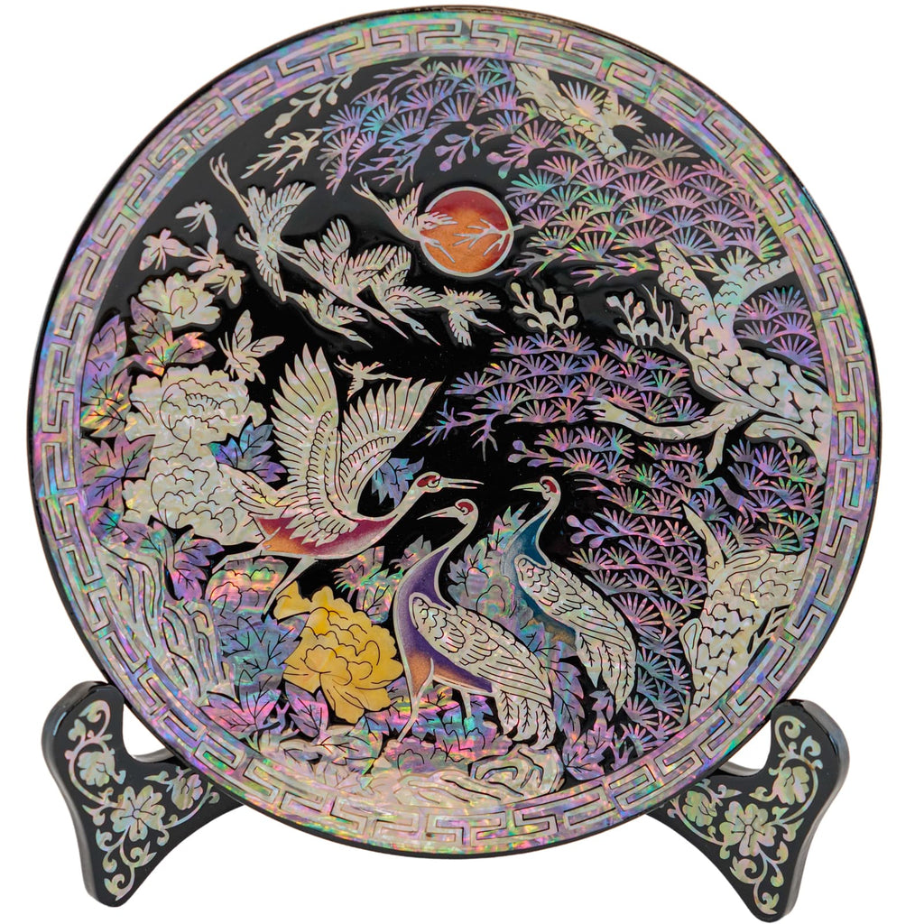 A decorative plate showcasing a peacock with an expanded tail amid flowers, displayed on a stand with mother-of-pearl details.