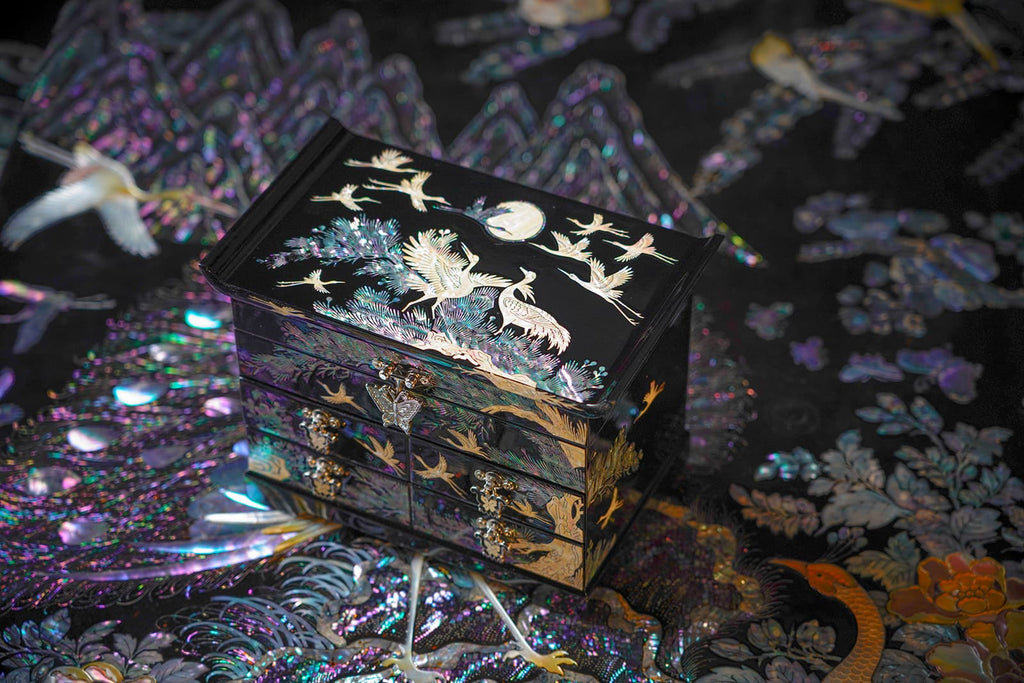 A luxurious black lacquer jewelry box adorned with a radiant mother-of-pearl crane and pine tree design, perfect for safeguarding precious items.