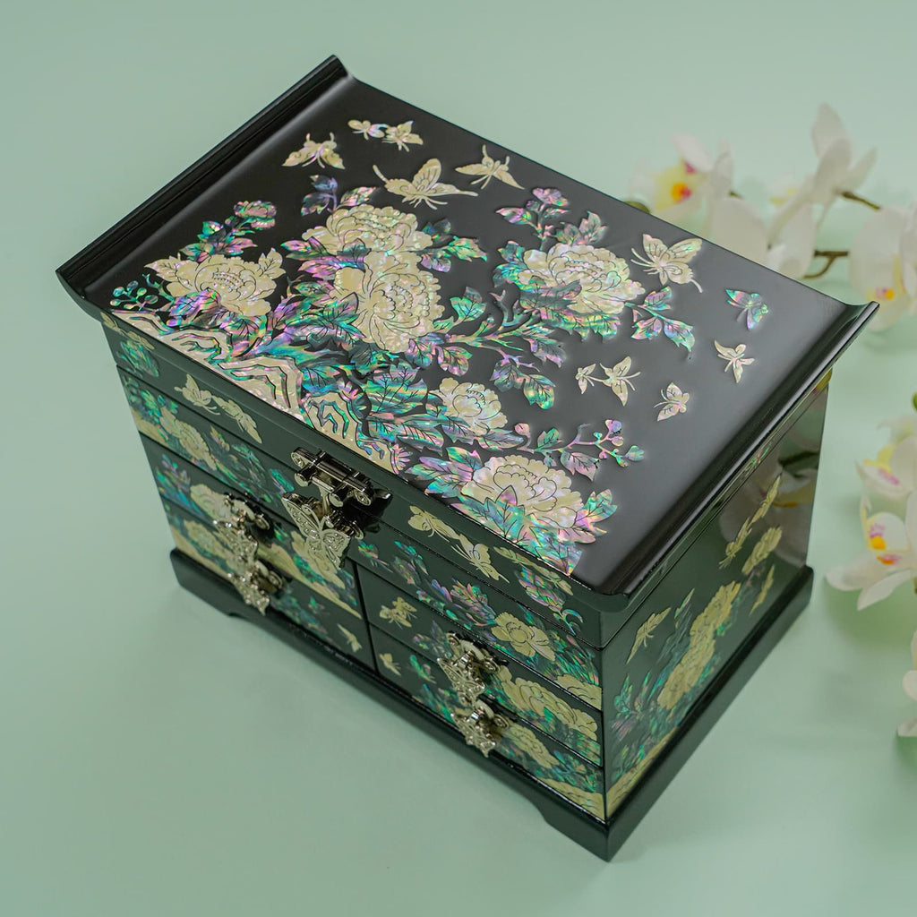 A mother-of-pearl inlaid jewelry box with detailed floral motifs on a teal background.