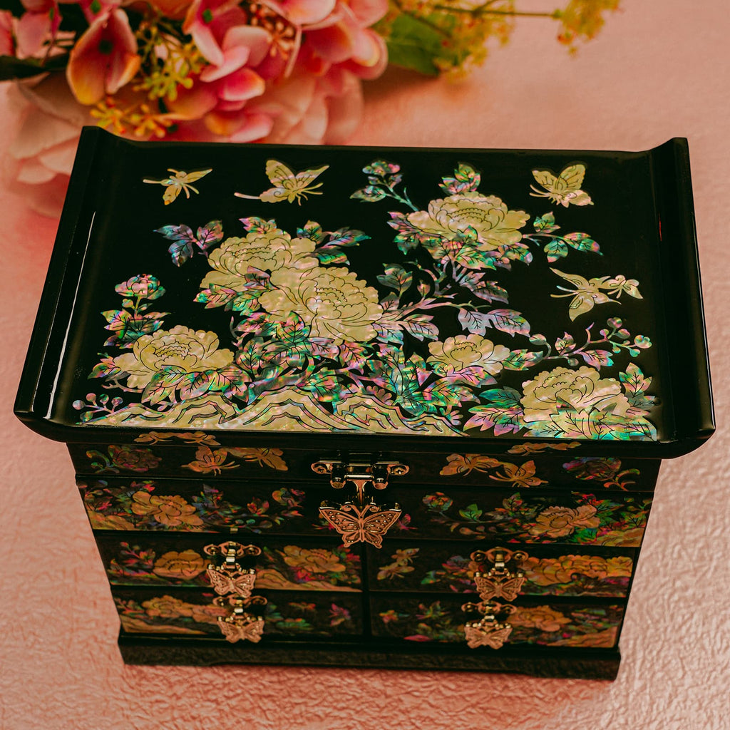 A mother-of-pearl inlaid jewelry box with intricate floral design on a coral pink background.