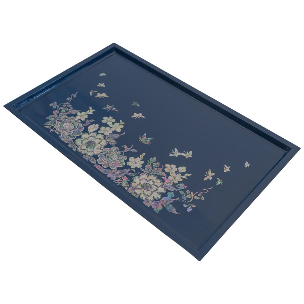 An angled view of a rectangular dark blue tray adorned with a floral and butterfly Mother of Pearl inlay pattern along the lower side, with a sleek blue border.