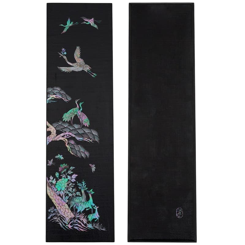 A narrow wooden tray covered in black hemp cloth with an ornate mother-of-pearl design depicting crane and deer.