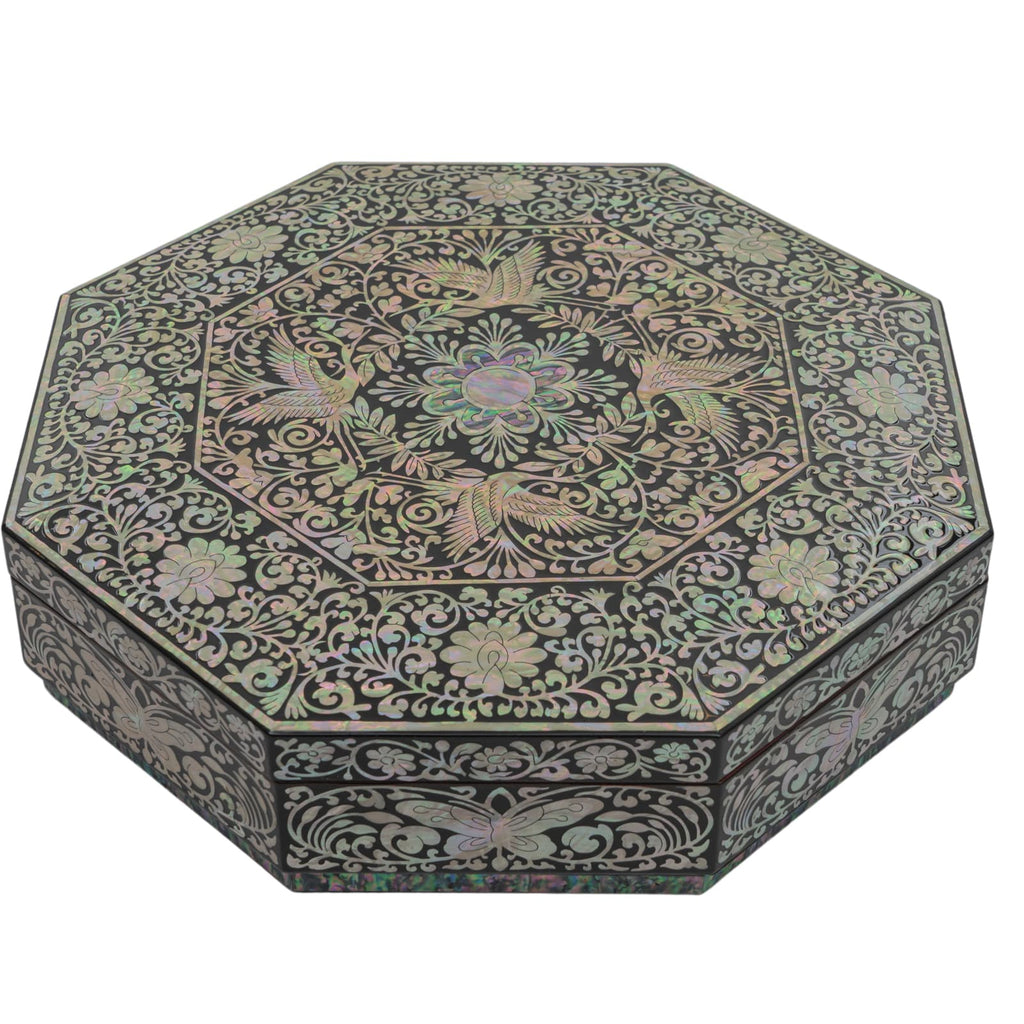 An intricately designed Mother of Pearl octagonal box with a floral pattern on the lid, closed, set against a neutral background.