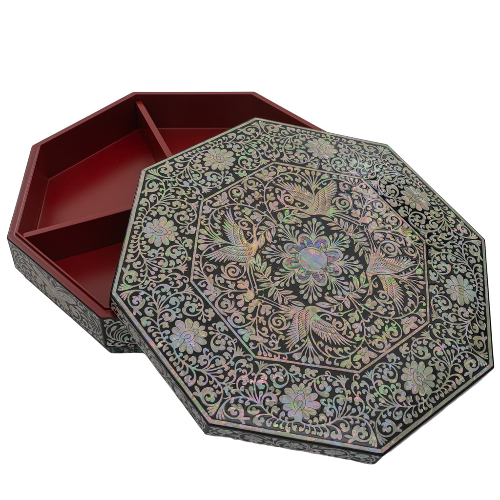 An octagonal lacquer box with intricate Mother of Pearl detailing on the lid and a rich red interior, presented against a white background.