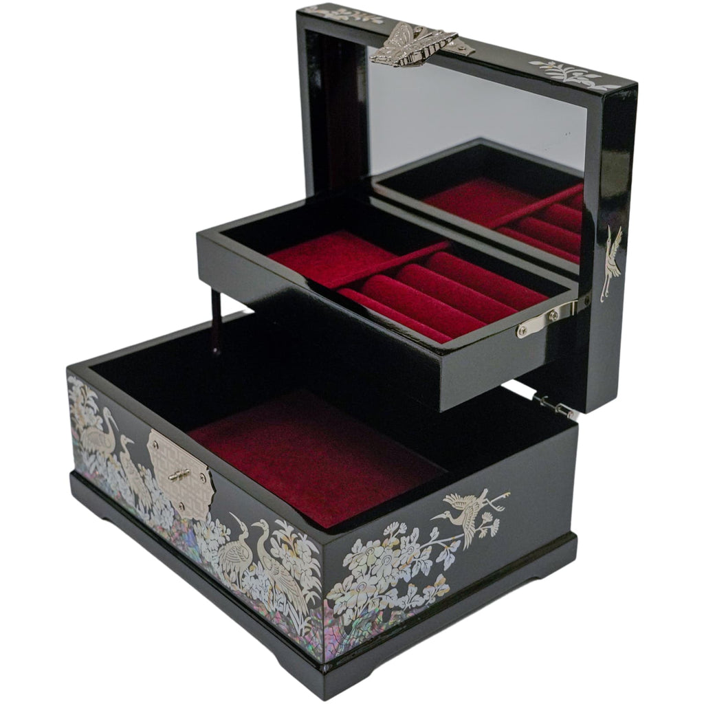 An open Mother of Pearl jewelry box with a red velvet-lined interior, showcasing compartments for rings and more storage beneath.