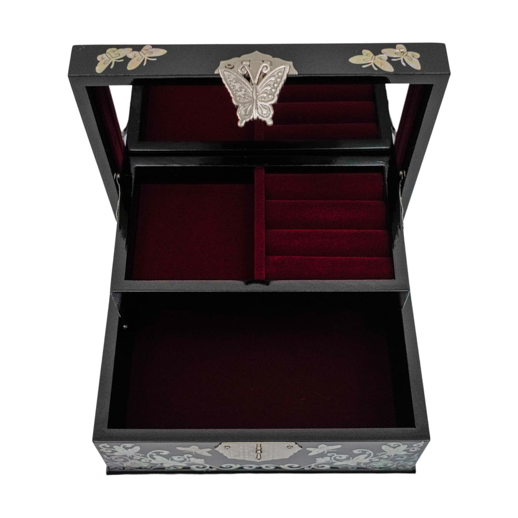 An open black jewelry box with mother-of-pearl inlay on the lid, velvet-lined compartments inside, and a butterfly-shaped metal piece on the top compartment.